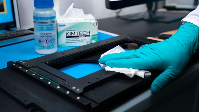 An image of a Zaber linear stage being wiped by a gloved hand.