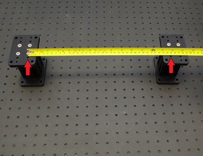 Loosely mount AP202Hxxxx risers to a breadboard or other mounting surface using the provided M6 x 16 mm low profile screws (longer of the provided screws) and a 4 mm hex key. See Product Overview for spacing between the red arrow indicated holes for your gantry configuration. Install screws until snug, then back off a little to allow alignment. Repeat until all screws are present. You may wish to leave the risers loose or just snug until complete assembly is done, then loosen and re-align as needed. Space additional risers for a single stage as far apart as possible (or equally spaced if using more than two), along the travel of the X-axis stages.